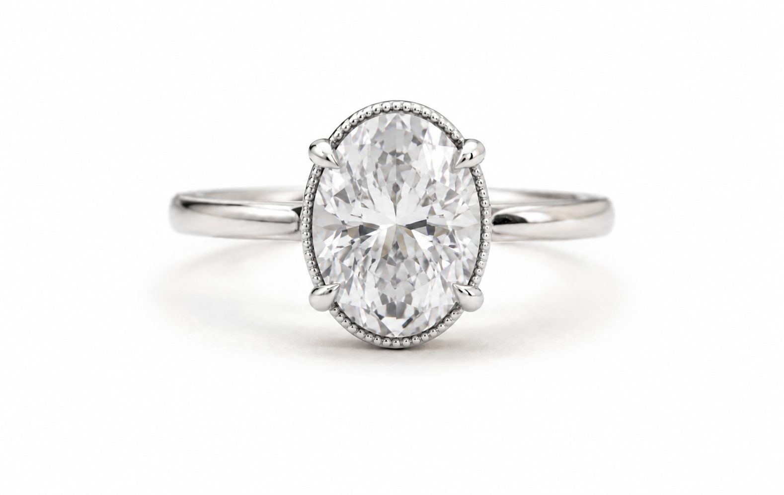 An oval-cut diamond engagement ring with a silver-toned band and a delicate milgrain border around the stone, set against a plain white background.